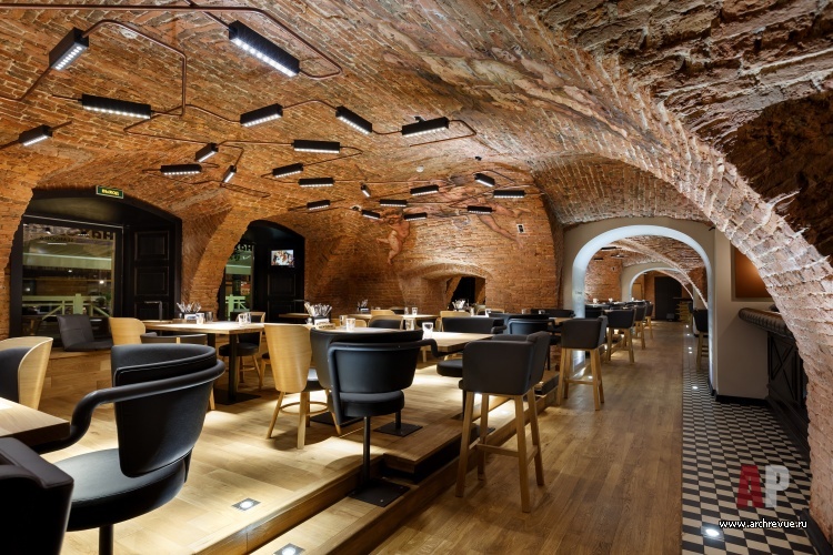 Рыбный ресторан с кирпичными стенами, сводчатыми потолками и скандинавской мебелью